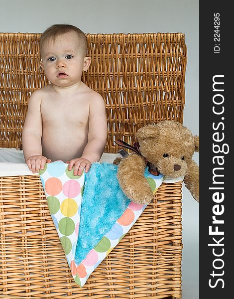 Image of cute baby and teddy bear peeking out of a wicker trunk