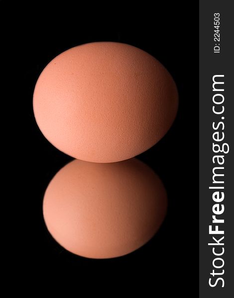 Chicken egg on mirror over black background