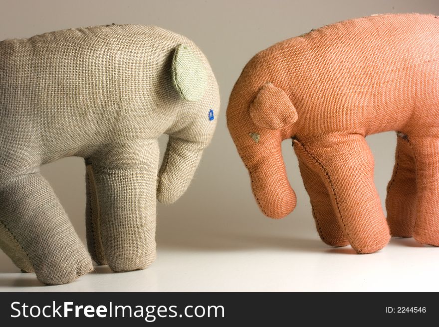 Small stuffed elephants isolated on white background butting heads with each other. Small stuffed elephants isolated on white background butting heads with each other