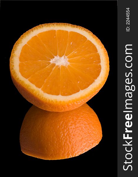 Sliced orange on mirror over black background