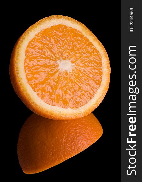 Sliced orange on mirror over black background