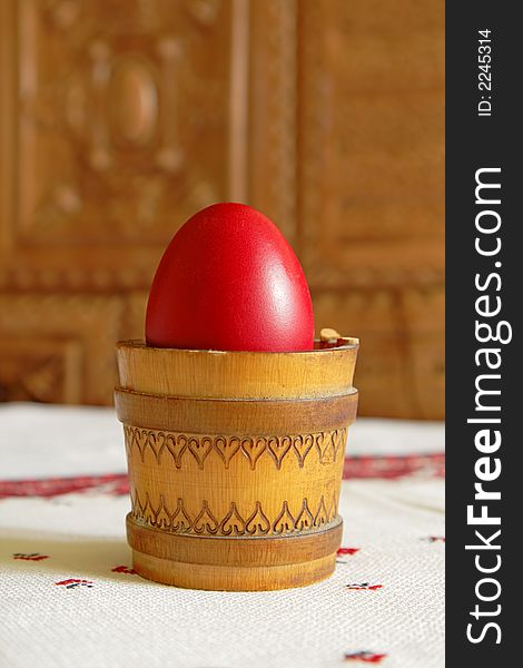 Red Easter egg in a traditional wooden canister with light reflection.