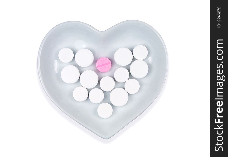 White and pink pills in a heart shaped bowl