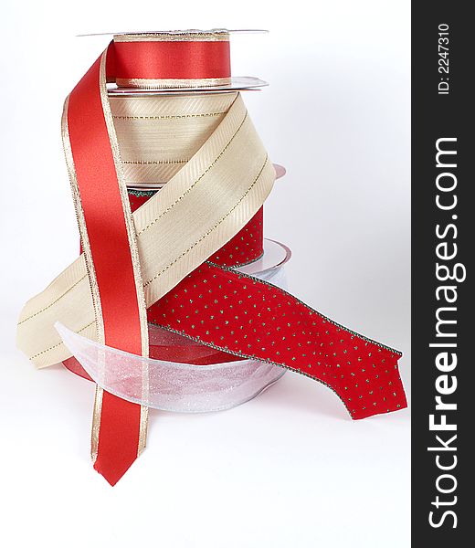 Tall stack of rolls of metallic ribbons in gold, red, and silver, isolated on white background. Tall stack of rolls of metallic ribbons in gold, red, and silver, isolated on white background