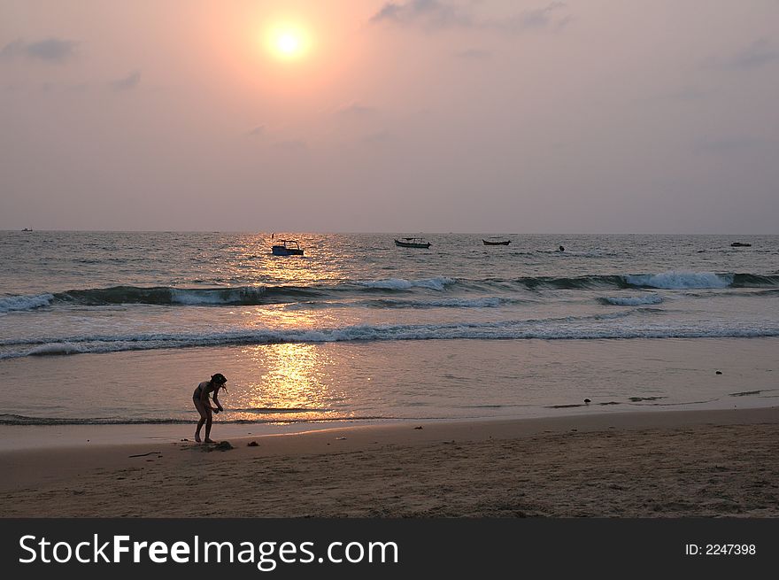 A kid collecting sand to make a sand a castle. A kid collecting sand to make a sand a castle