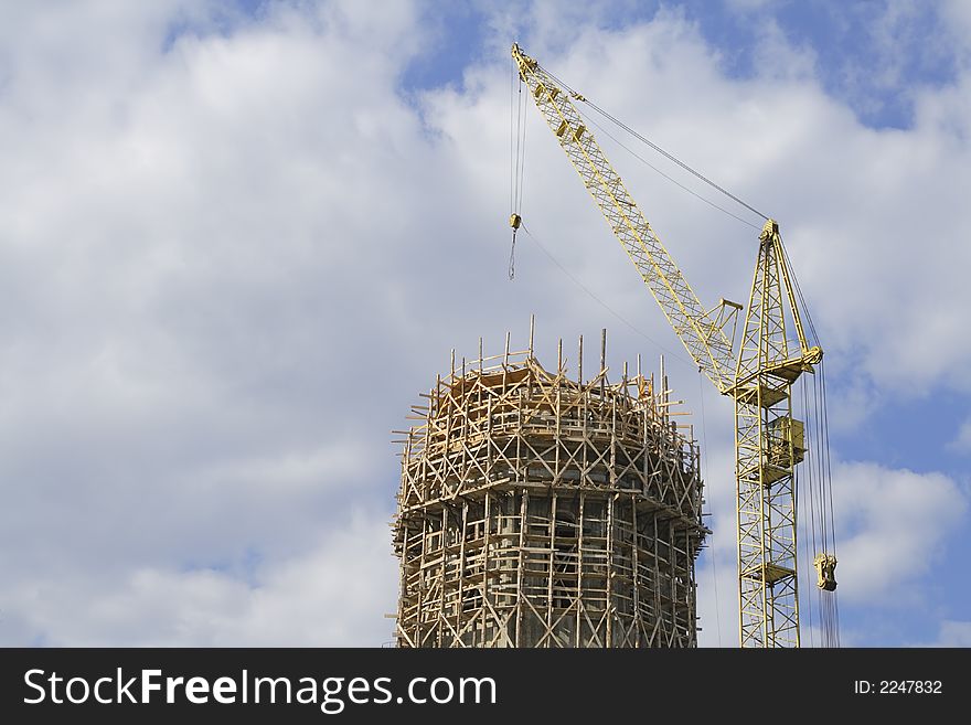 Image of a crane near a scaffold over a cloudy sky. Image of a crane near a scaffold over a cloudy sky.