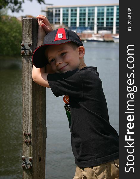 Young boy leaning on a post next to the river. Young boy leaning on a post next to the river