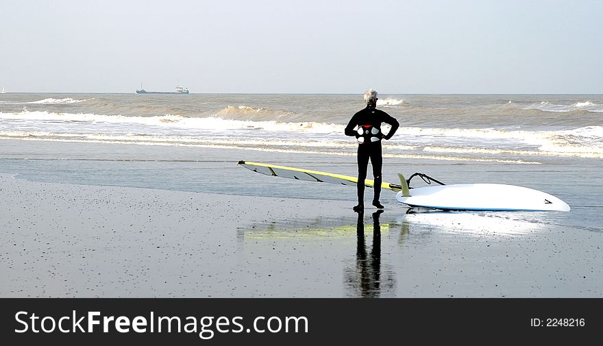 Surfer is surveying the ocean before going to surf along the North Sea coast in Belgium. Surfer is surveying the ocean before going to surf along the North Sea coast in Belgium.