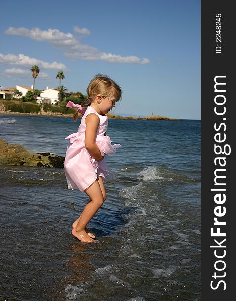 Young girl jumping the waves as they roll up the beach in Spain