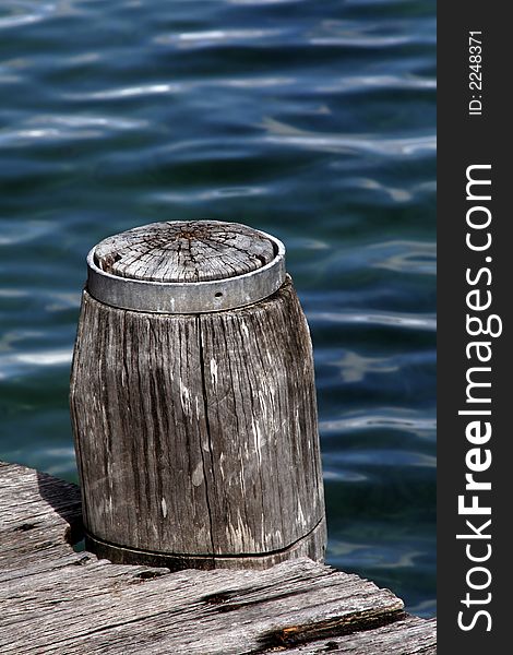 Wooden Pole Marking A Footpath Next To The Blue Ocean Surface