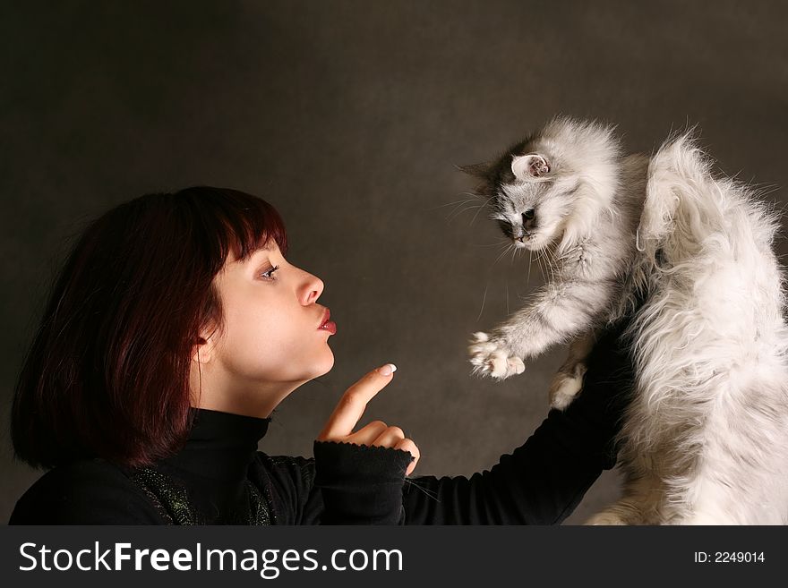 The beautiful girl with a kitten on a dark background. The beautiful girl with a kitten on a dark background