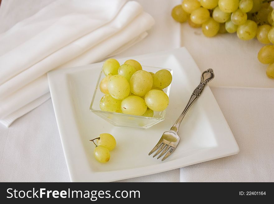 White grapes lying on a plate with a small plug.