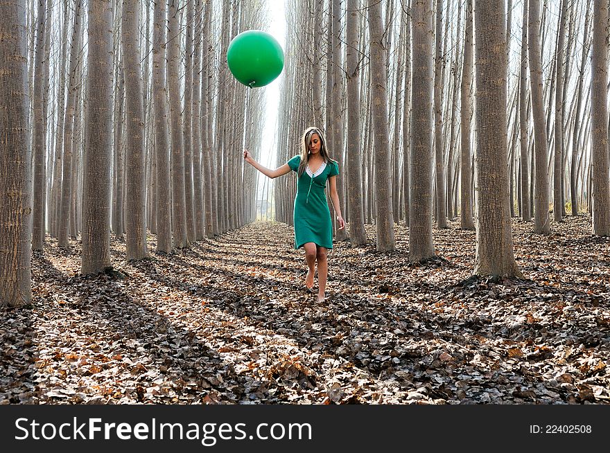 Beautiful blonde girl, dressed in green, walking into the forest. Beautiful blonde girl, dressed in green, walking into the forest