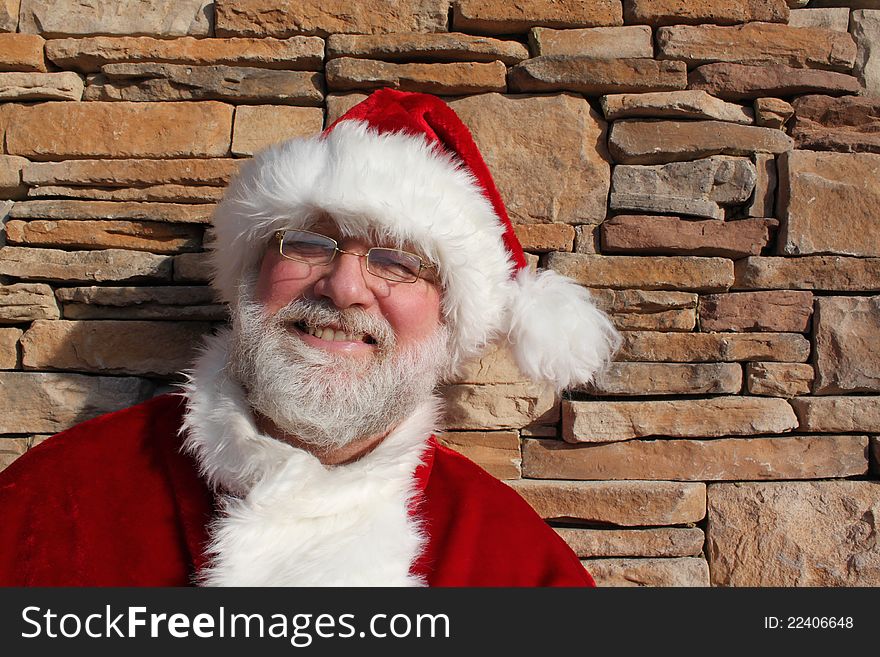 Santa Claus standing against a stone wall. Santa Claus standing against a stone wall.