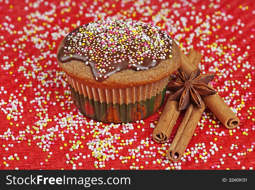 A sprinkled Christmas muffin, with cinnamon and anise, on red background