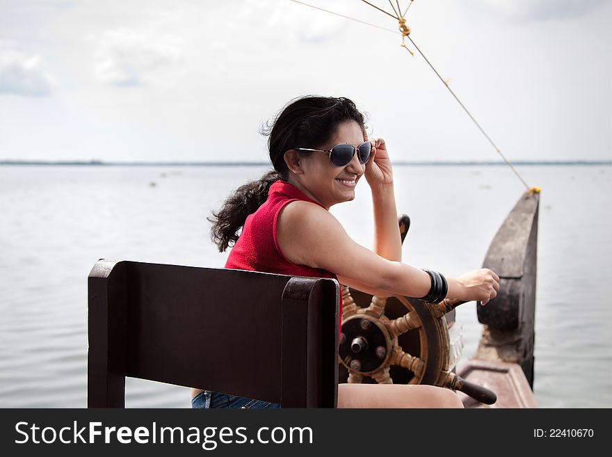 A happy young girl, wearing sun glasses and red top, enjoying nature while sailing house boat. A happy young girl, wearing sun glasses and red top, enjoying nature while sailing house boat