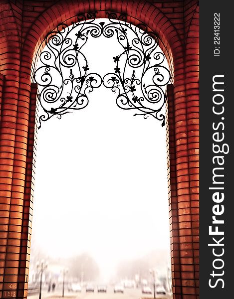 The brick arch in vintage style, is decorated by patterns from metal. Against the sky