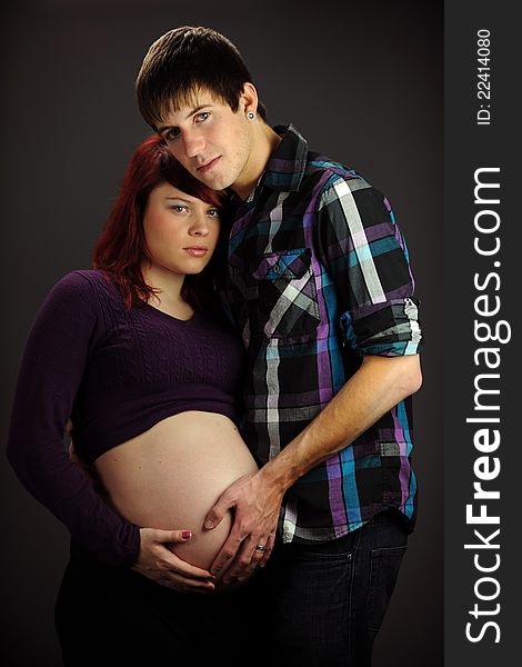 Young Expecting couple isolated on a dark neutral background