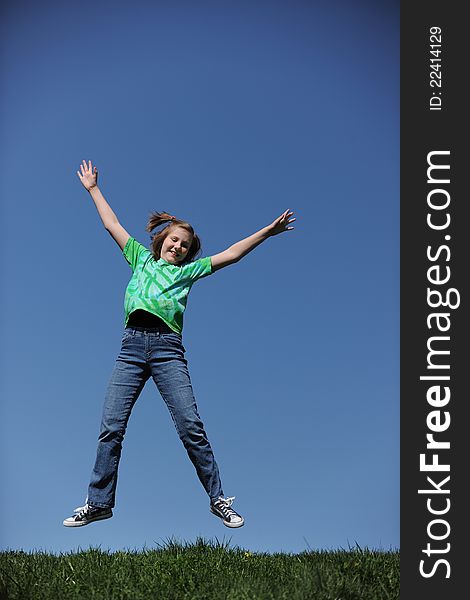 Young Girl Jumping on a sunny day against a blue sky. Young Girl Jumping on a sunny day against a blue sky