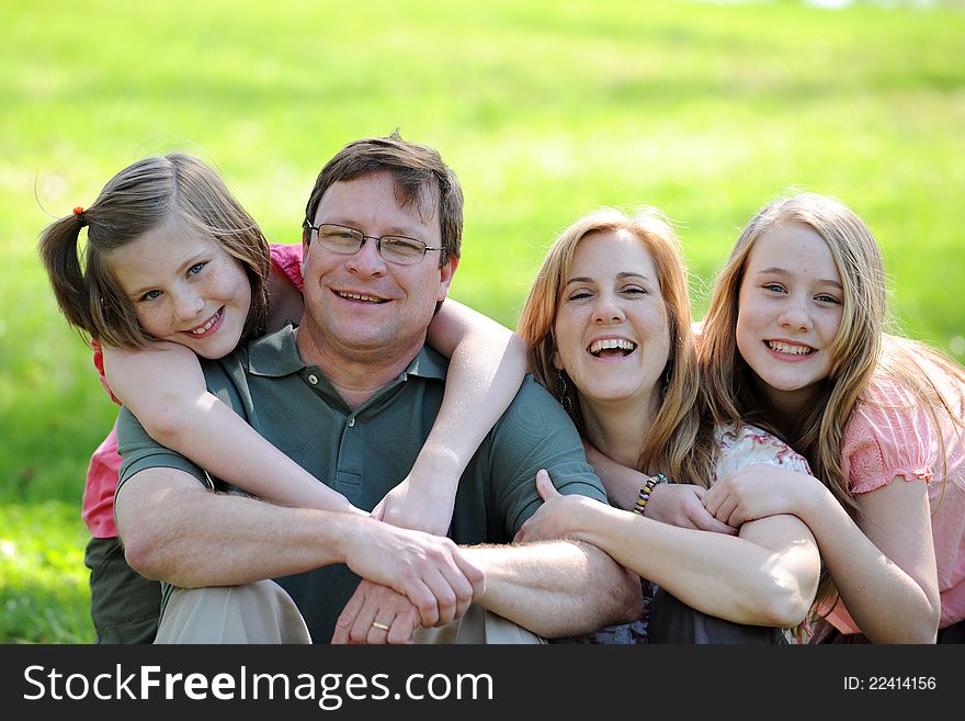 Young Couple with daughters smiling and hugging outdoors