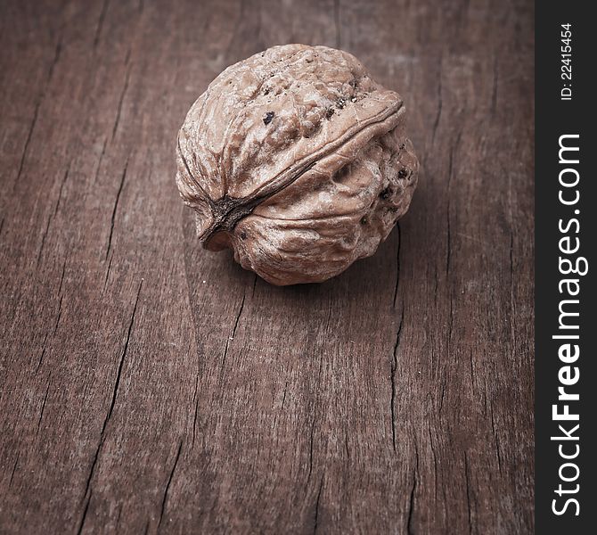 Closeup of one walnut piece on wooden background;