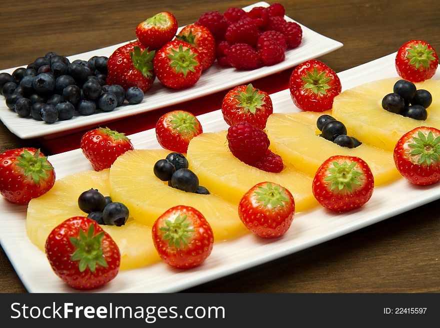 Pineapple slices with berries on wooden table