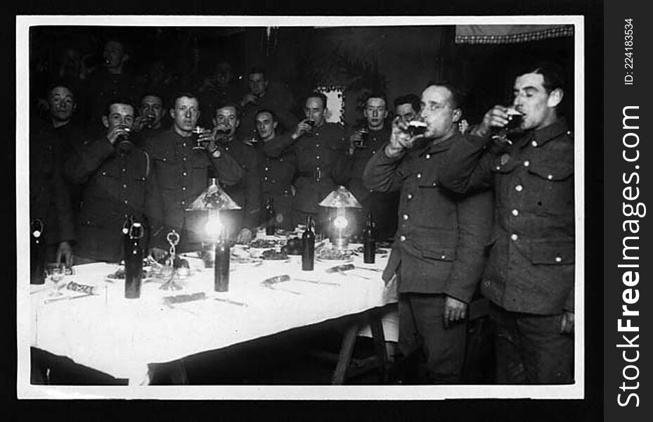 Soldiers at Christmas. The men are raising their glasses. 

The caption on the previous photograph in the sequence reveals that the glasses were filled with beer, not wine. There was not much cheer for the soldiers on the front line. It is difficult not to wonder whether this picture was not set up by the photographer as a piece of reassuring propaganda for publication in the newspapers back home.

[Original reads: &#x27;Drinking the King&#x27;s health back in their billets.&#x27;]

digital.nls.uk/74545982