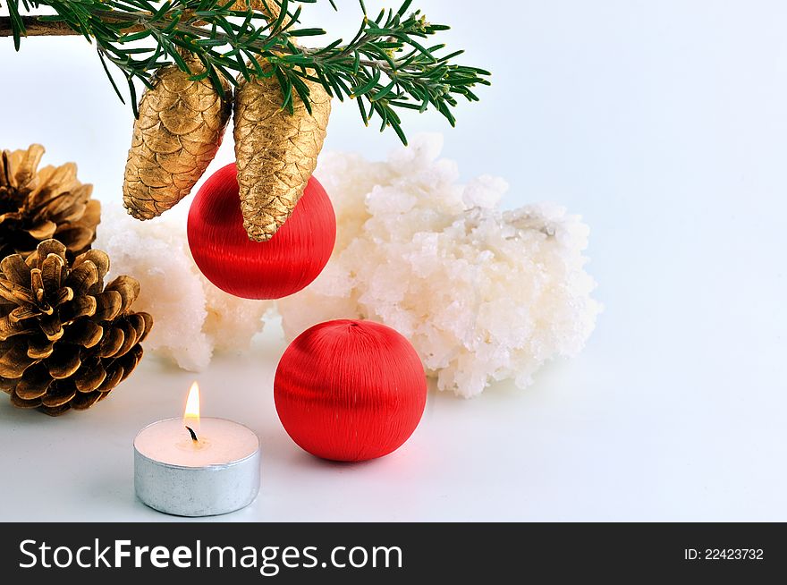 Red balls, cone spruce,  and sprigs to decorate for Christmas against a white background and candles burning. Red balls, cone spruce,  and sprigs to decorate for Christmas against a white background and candles burning