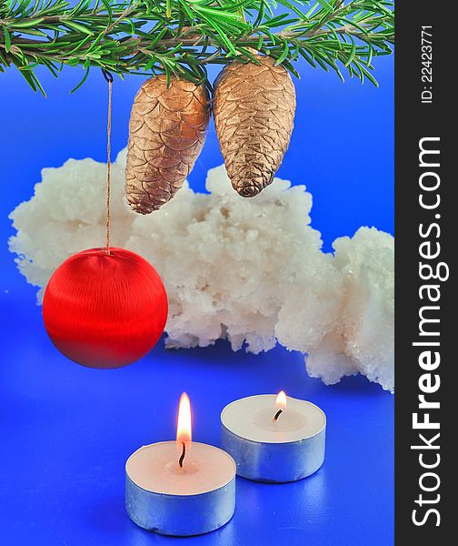 Red balls, cone spruce, ice and sprigs to decorate and candles burning for Christmas, against a blue background. Red balls, cone spruce, ice and sprigs to decorate and candles burning for Christmas, against a blue background