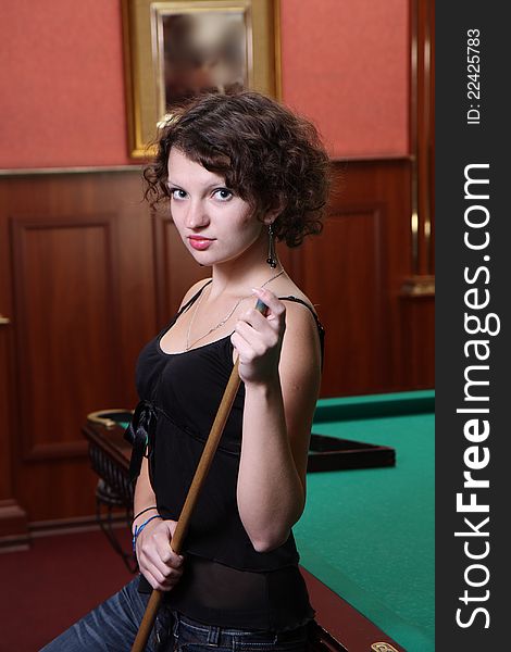 The beautiful blonde aims in the course of game at billiards. The beautiful blonde aims in the course of game at billiards