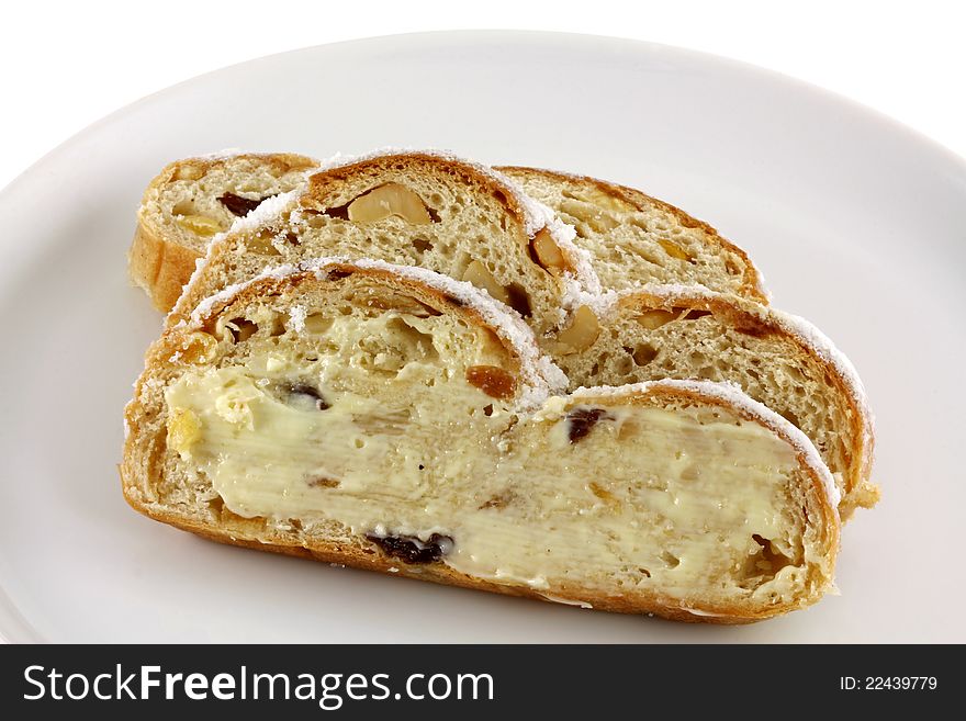 Butter on a slice of homemade Christmas stollen cake with raisins, nuts, spices and chopped dried fruit. Butter on a slice of homemade Christmas stollen cake with raisins, nuts, spices and chopped dried fruit