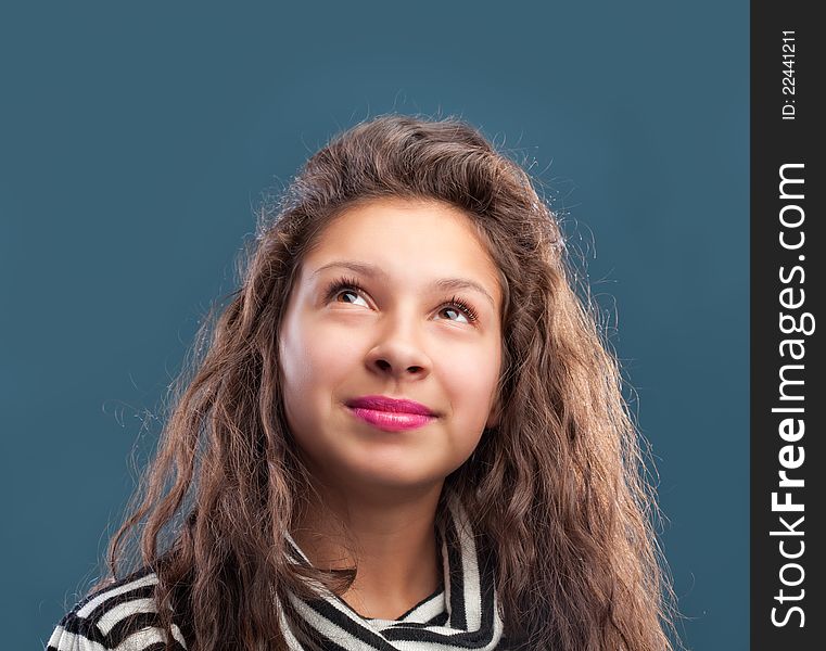 Beautiful young girl looking up isolated on blue background