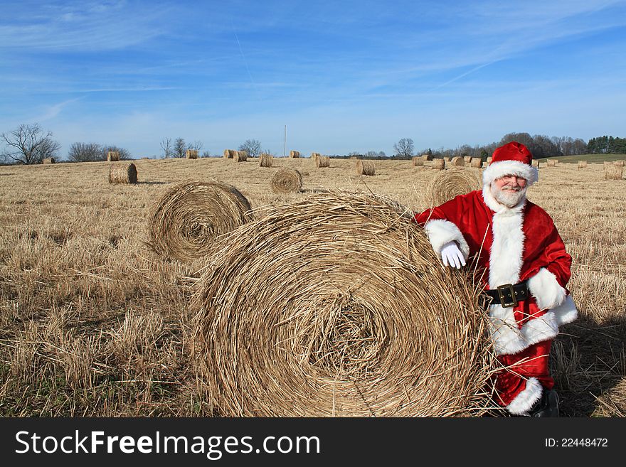 Santa standing against a bale of hay in a hay field. Santa standing against a bale of hay in a hay field.