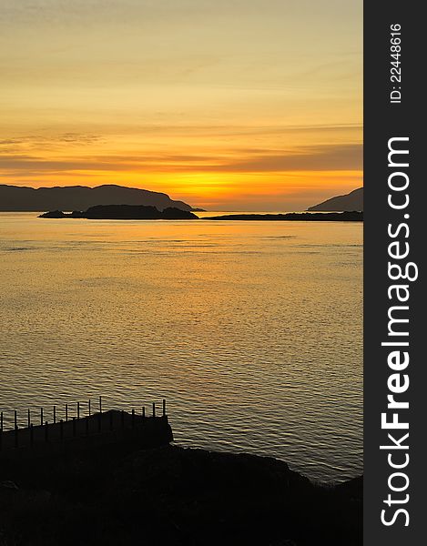 A romantic sunset shot showing the Corryvreckan narrows in the distance, over the sound of Jura, between the islands of Scarba and Jura. These narrows contain one of the largest tidal whirlpools in the world. The shot was taken from the old steamer pier at Aird in Argyll, Scotland. A romantic sunset shot showing the Corryvreckan narrows in the distance, over the sound of Jura, between the islands of Scarba and Jura. These narrows contain one of the largest tidal whirlpools in the world. The shot was taken from the old steamer pier at Aird in Argyll, Scotland.