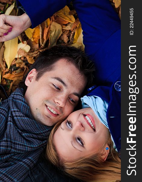 Portrarit of a happy young couple lying on fallen leaves in the park. Portrarit of a happy young couple lying on fallen leaves in the park.