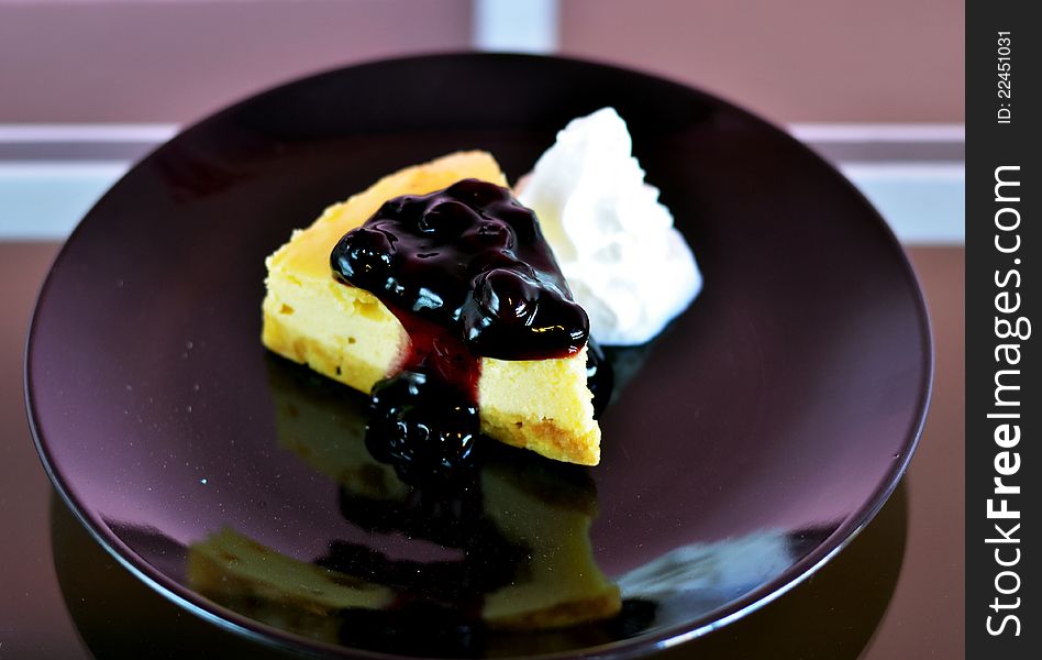 A slice of blueberry cheese cake served with whipped cream