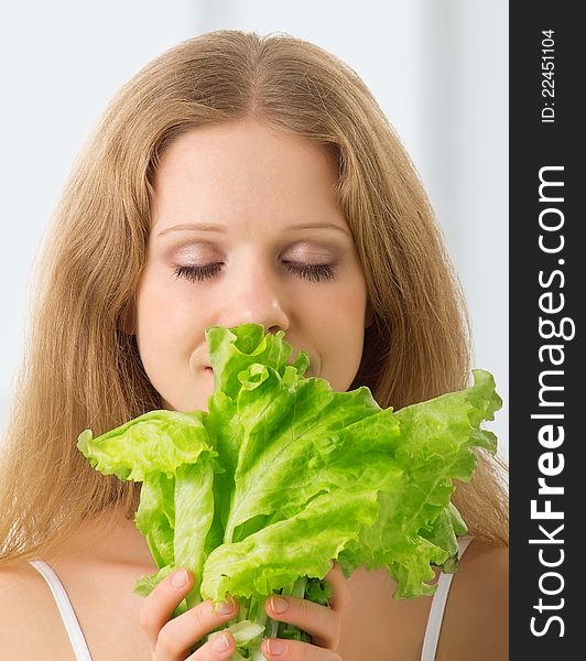 Young beautiful woman with green lettuce with eyes closed. Young beautiful woman with green lettuce with eyes closed
