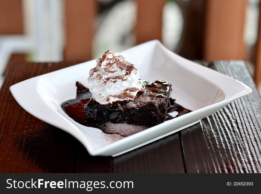 Brownie cake served with chocolate sauce and whipped cream