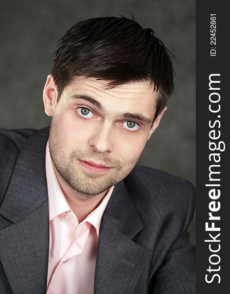 Young business man in gray suit on gray background