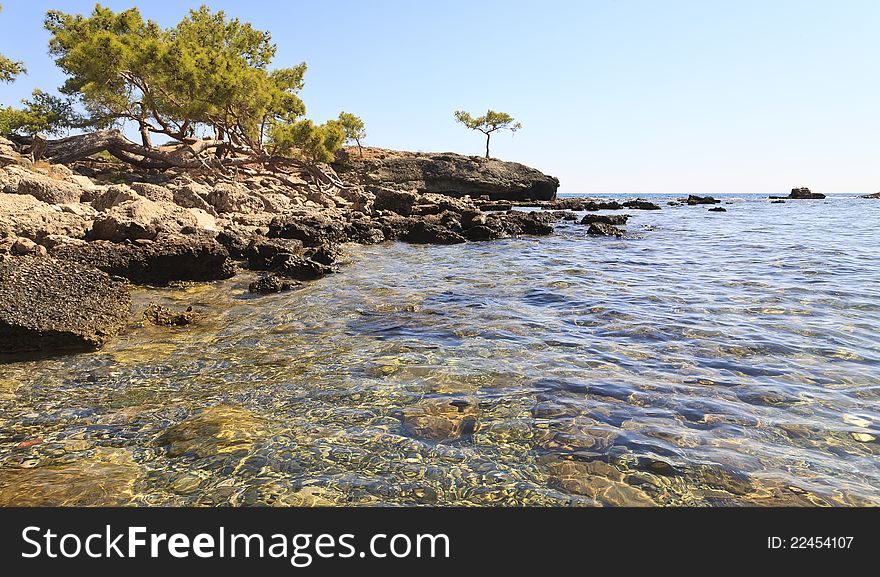 View from beach at Phaesalis, Antalya Turkey, showing clear water, rocks and trees