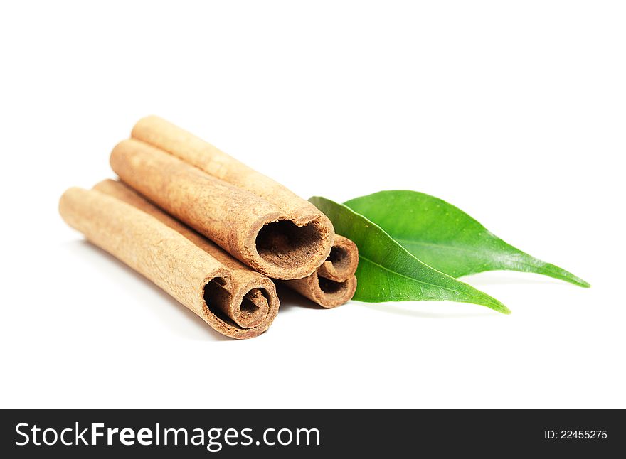 Cinnamon sticks and green leaves on a white background