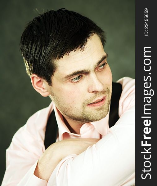 Thoughtful young man in pink shirt on gray background