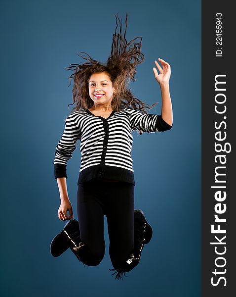 Young beautiful happy woman jumping against blue background