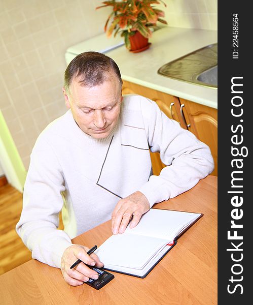 Older man concentrating on job, using calculator at home. Older man concentrating on job, using calculator at home