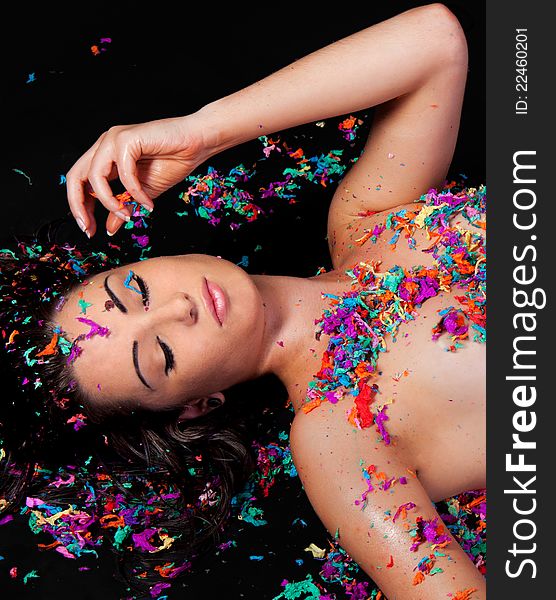 A fun image of a pretty young woman, covered in bright, colorful pieces of confetti and playing with it. A fun image of a pretty young woman, covered in bright, colorful pieces of confetti and playing with it