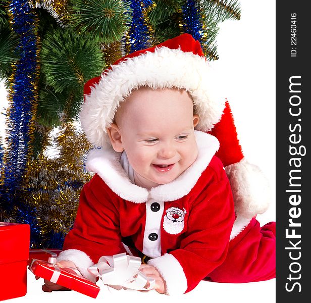 Little baby boy wearing Santa's costume sitting and holding a box with christmas 
presents