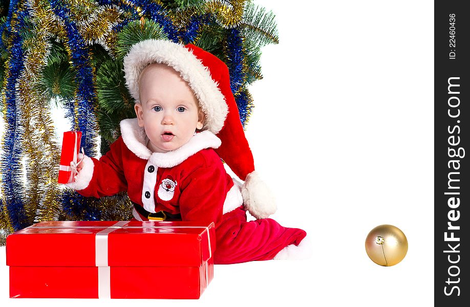Little baby boy wearing Santa's costume sitting and holding a box with christmas presents