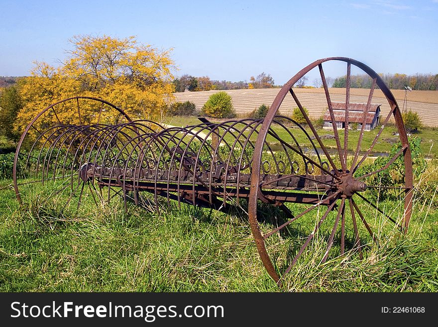 A rustic farm rake sits abandon in a farm pasture. A rustic farm rake sits abandon in a farm pasture.