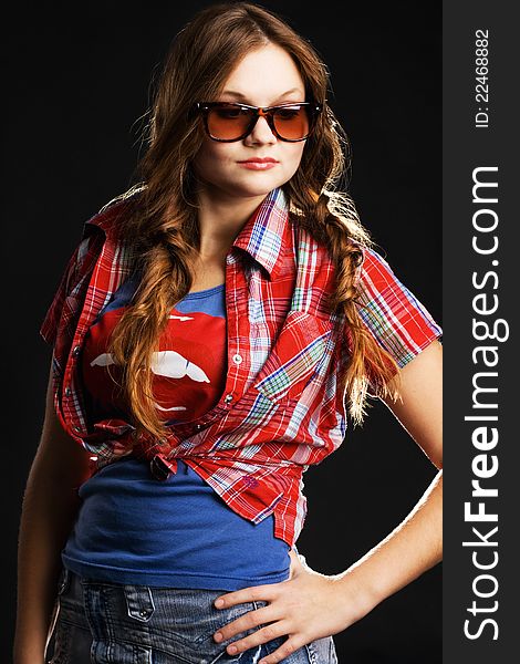 Stylish girl in sunglasses against black background