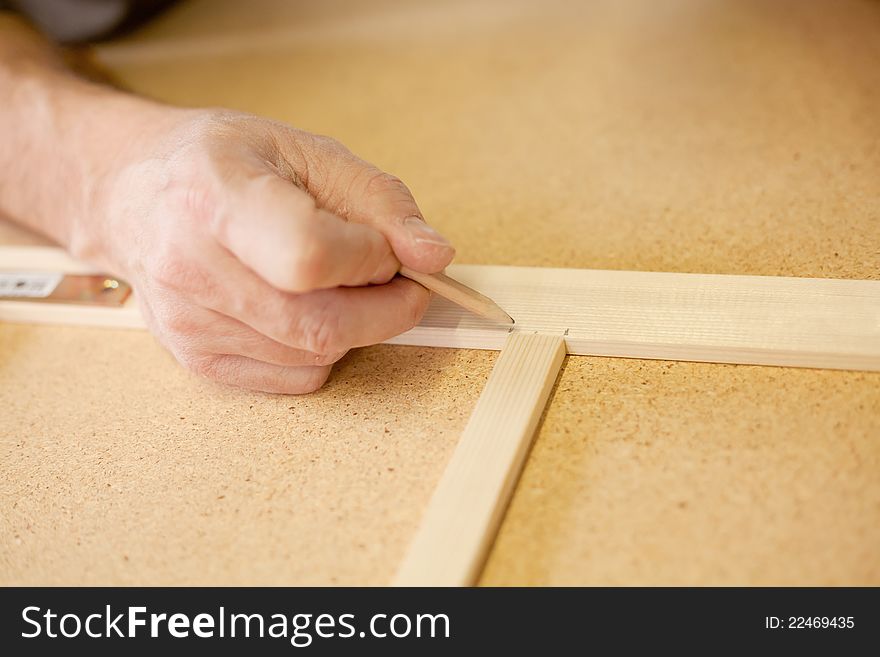 Marking wood with a black pencil on  a workbench